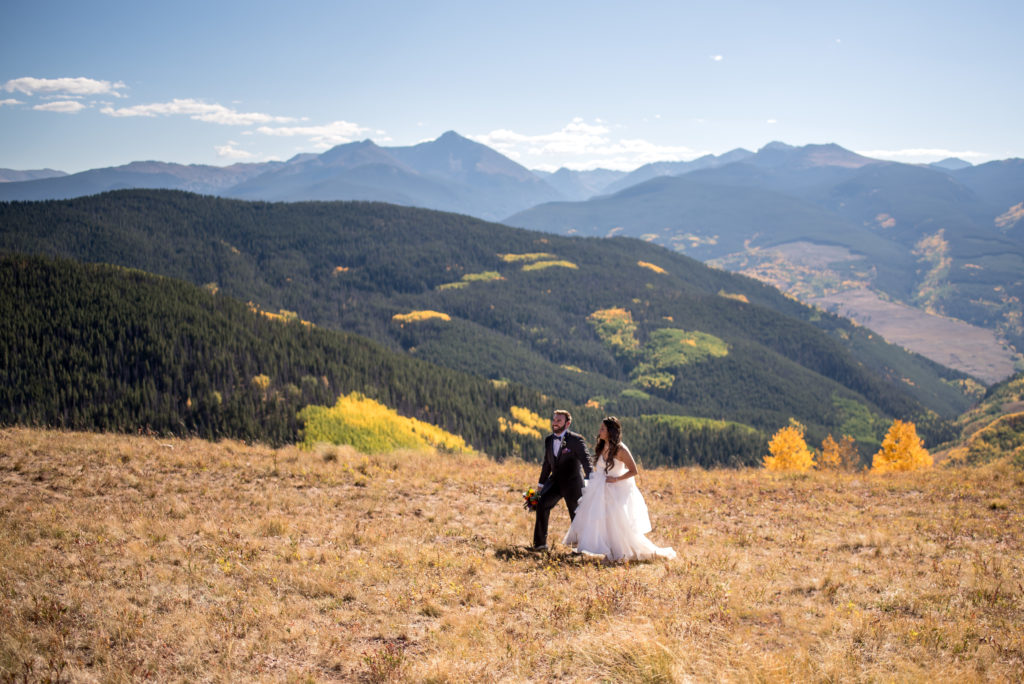 Bride and groom walking at the top of Vail Mountain Ski Resort with fall colors in Vail, Colorado
