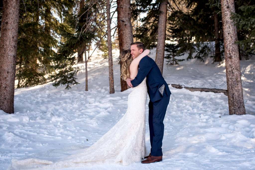 Bride and groom hugging in the snow at Breckenridge Ski Resort in the woods on their Colorado winter elopement day 