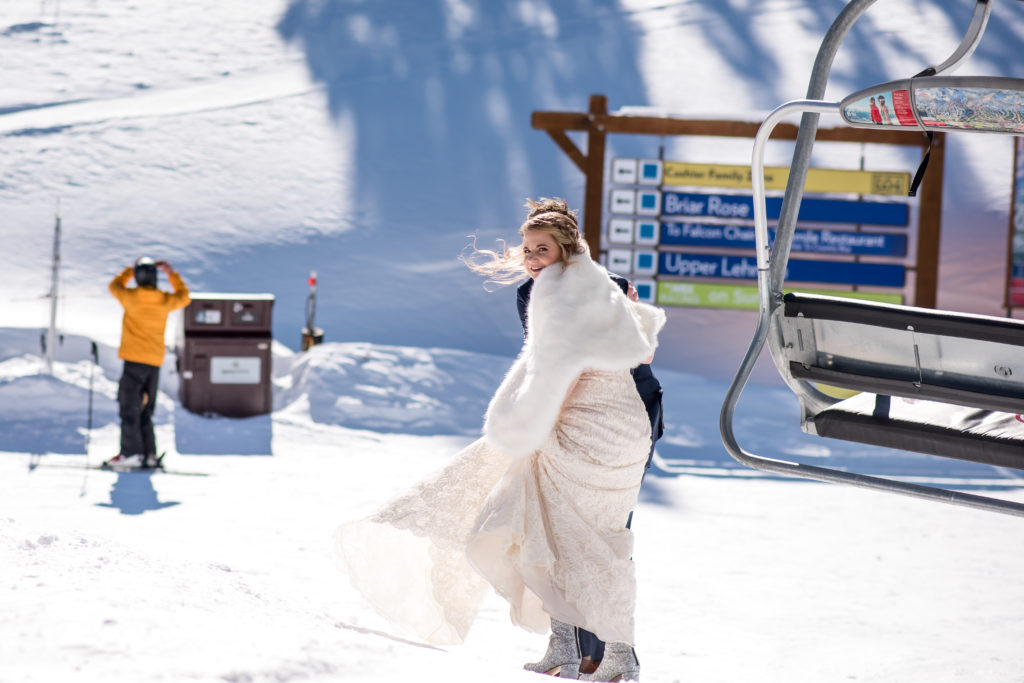 Bride getting off chairlift at the top of Breckenridge mountain during Colorado winter elopement in Breckenridge