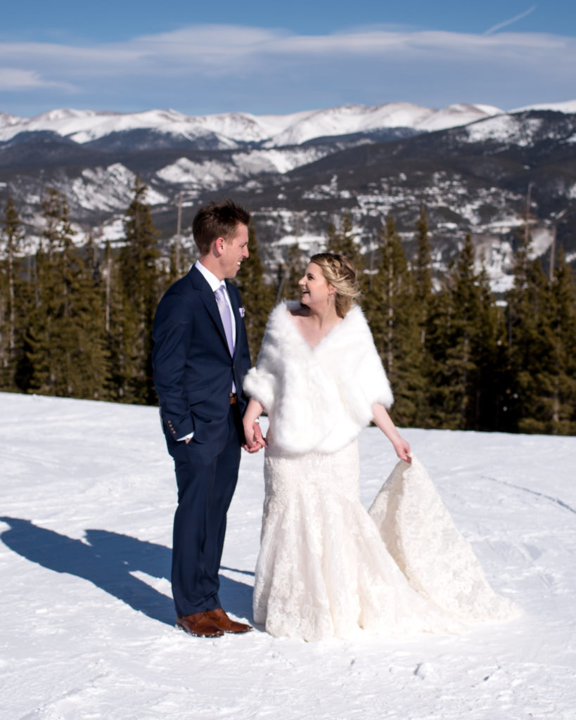 Bride with winter shawl over her wedding dress with groom at the top of the mountain in Breckenridge during their ski resort winter elopement in Colorado
