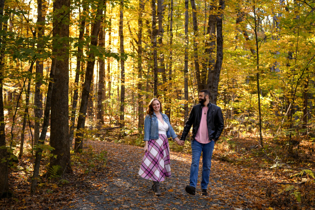 Couple walking through a forest trail with vibrant fall leaves