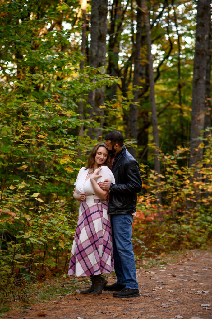 Couple in warm embrace surrounded by fall foliage in the woods