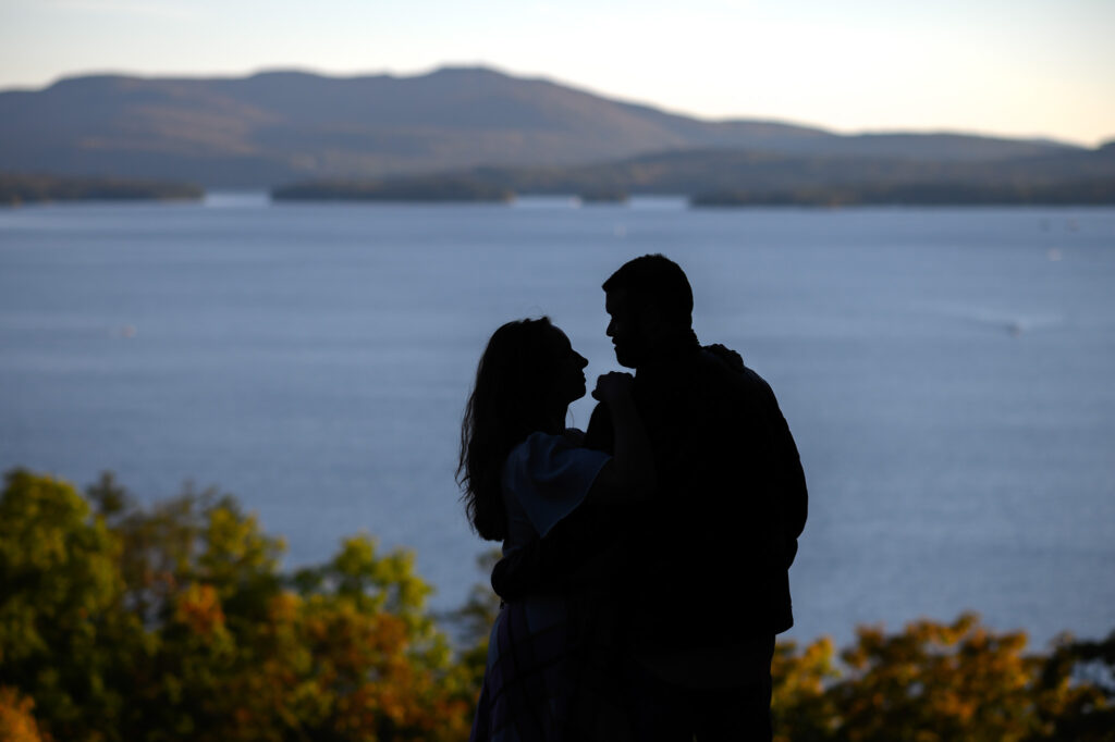 Silhouette of couple looking at eachother with lake sunapee in the background